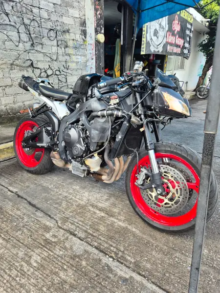 Moto naked con rines rojos frente a la entrada del taller Style Riders Garage
